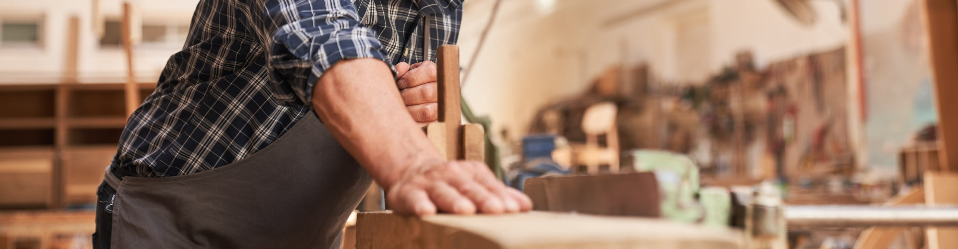 Woodworker using hand plane to smooth wooden board in workshop – professional carpentry and woodworking tools in use